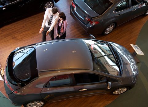 Elevated view of car salesman explaining car features to customer