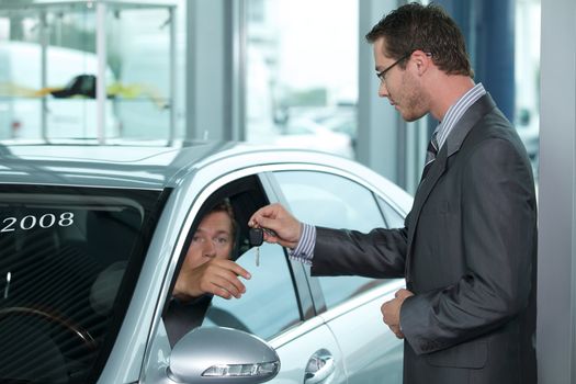 Man getting keys to new car through salesperson
