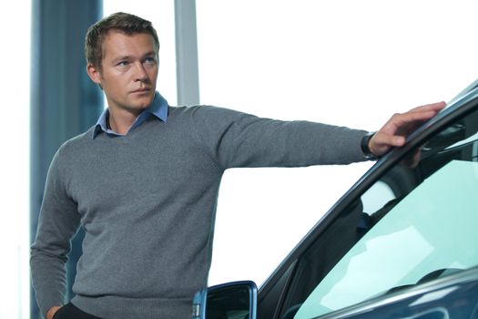 Young man standing by new car
