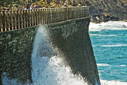 Water arrives at the border and brake up very hard against rocs. In th background we can see ocean and other rocs.