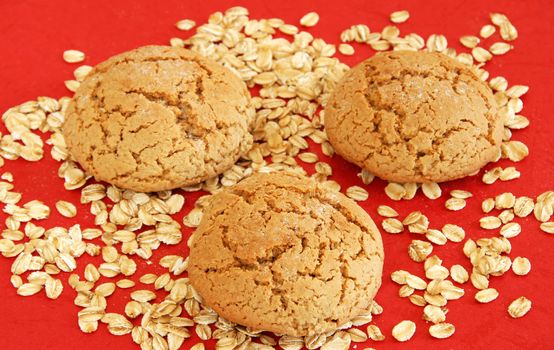 three fresh appetizing oatmeal cookies over red background