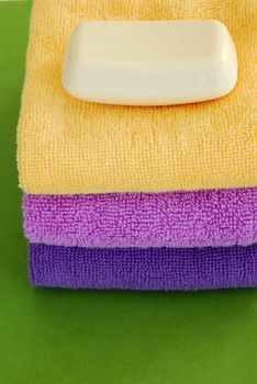 pile of colorful towels with white soap over green background