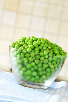 young fresh organic green spring peas in glass bowl