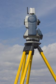 Side of theodolite against cloudy sky.