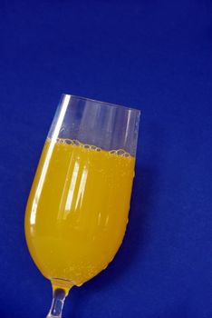 glass of yellow juice over dark blue background