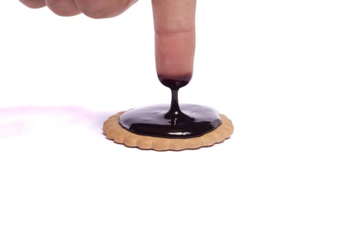 View of a round biscuit isolated on a white background with a drip of dark chocolate.