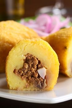 Peruvian dish called Papa Rellena (Stuffed Potato) made of mashed potatoes and filled with meat and egg (Selective Focus, Focus on the front of the half papa rellena)