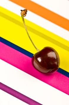 one ripe cherry on the colored background