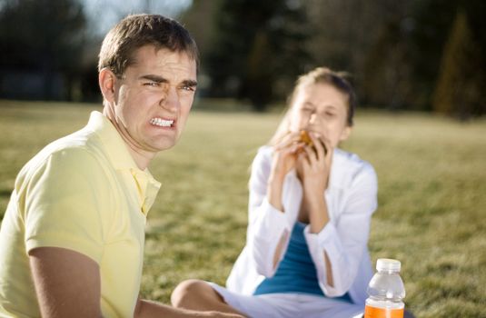 A guy cringing as his date stuff her face with food.