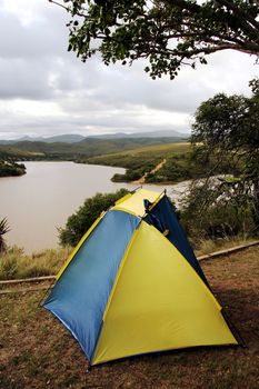 Small blue and yellow tent at a camping site next to a dam