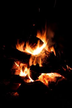 Glowing embers and flames of a camp fire at night