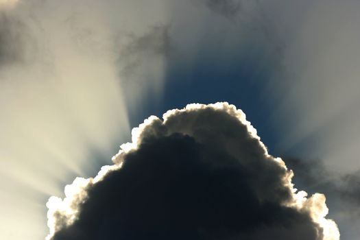 Billowing clouds and suns rays shining behind