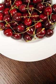 Looking down on a bowl of cherries sitting on a wooden table.
