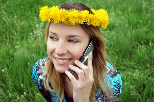 Blonde happy girl with dandelion diadem talking on mobile