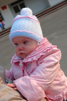 Pretty little girl in pink jacket on mother's hands.