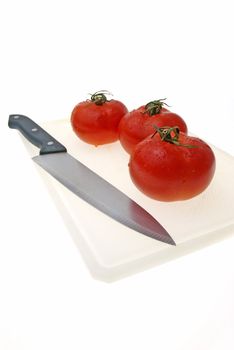 Cutting white plastic board with a knife and tomato isolated on a white background.