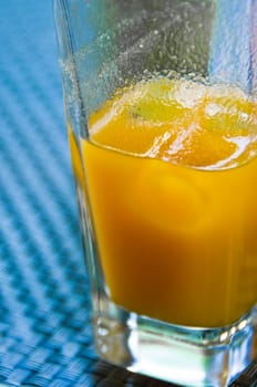 Fruit juice of apricots. In the bluish glass desk. The thick natural juice. With ice cubes in it.