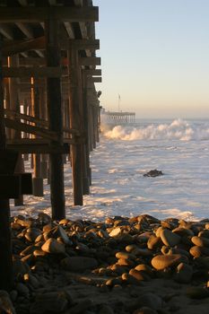 Ocean waves throughout at storm crashing into a wooden pier.