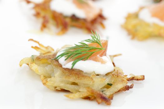 Bite sized potato rosti appetizer topped with fresh sour cream, smoked salmon and dill.