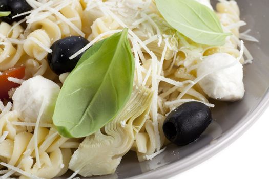 Fusilli pasta with black olives, mozzarella cheese, artichoke hearts and tomato slices, topped with fresh basil leaves. 
