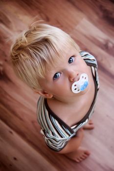 young little boy is looking up on the wood floor