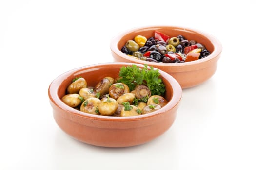 Marinated mushrooms and olives in earthenware bowls isolated on white background.