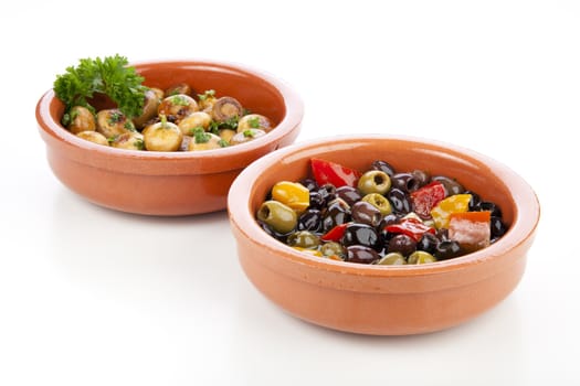 Marinated mushrooms and olives in earthenware bowls isolated on white background.