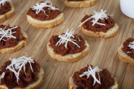 Fresh homemade sun dried tomato tapenade on toasted baguette topped with fresh grated cheese.