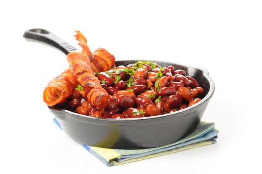 Baked beans and bacon served in a cast iron skillet.