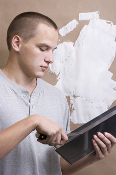 Caucasian man plastering a brown wall with white plaster.