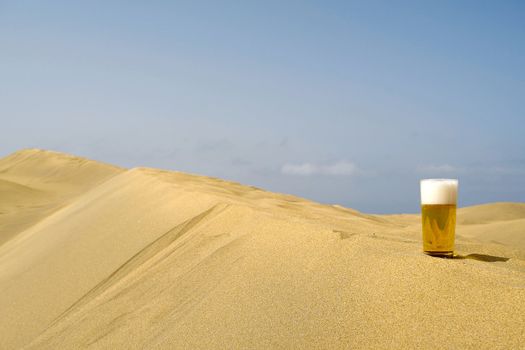 A glass of fresh beer in a desert. 