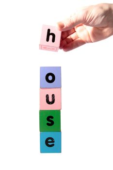 toy letters that spell house against a white background with clipping path with hand