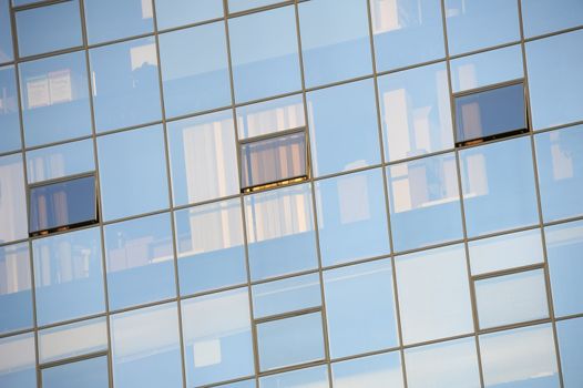 Detail of a glass-fronted office block with contents of offices faintly visible behind the glass. Suitable as abstract background.