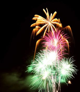 Multi-coloured firework bursts in the night sky. Space for text in the sky.