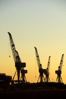 Cranes of a Glasgow shipyard silhouetted against the sky at sunrise/sunset (could be either). Space for text in the sky.