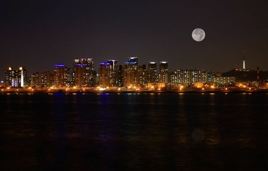 Impressive city skyline of Seoul in the Han River at full moon.