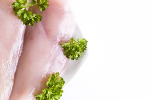 Raw chicken breasts on the plate with parsley - isolated