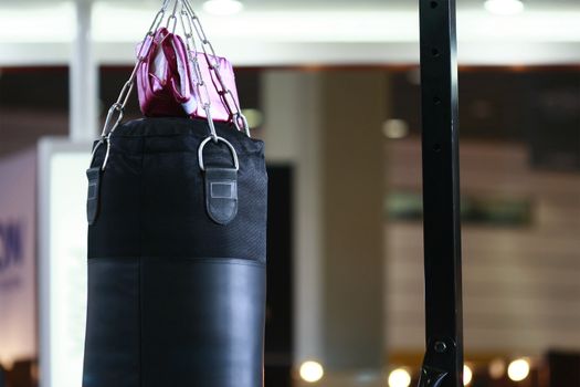 Boxing bag and a lady pink bag in a well lighted gym.