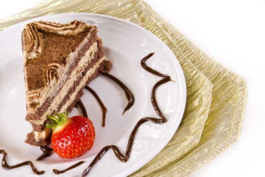 Tiramisu cake on plate with strawberry on gold napkin