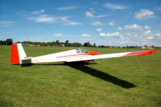 Olp plane on air field with blue and cloudy sky in the background.