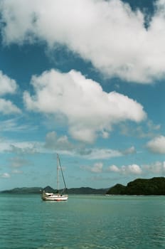 A yacht sailing on a clear day, with blue sky and green water