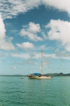 A yacht sailing on a clear day, with blue sky and green water