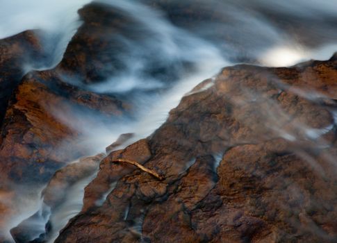 Fallen leaves in fall in river by edge of waterfall