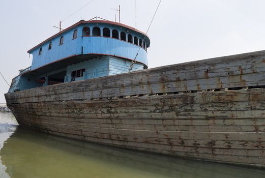 Blue rusty vessel in a canal in Jakarta harbor 