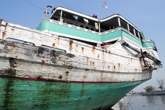 Blue rusty vessel in a canal in Jakarta harbor 