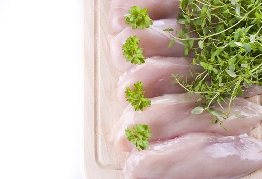 Raw chicken breasts on chopping board with herbs