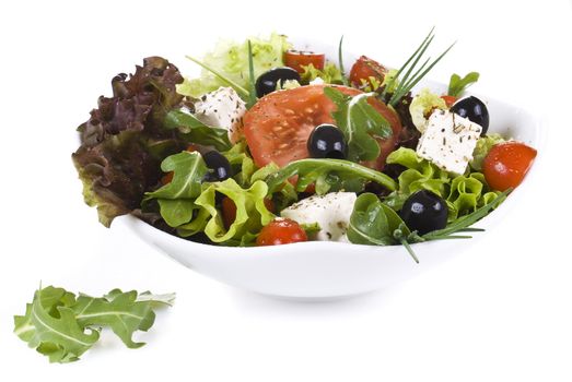 Vegetable salad with dropped leaves over white background