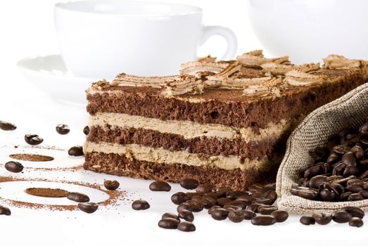 Tiramisu cake with bag of coffe beans and cup over white