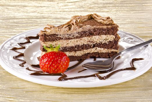 Tiramisu cake on plate with strawberry on gold napkin