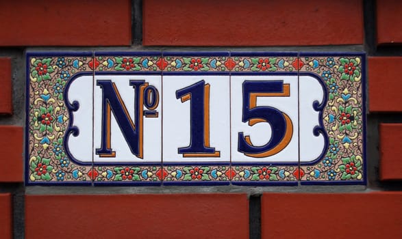 House number tile plaque with floral ornament. 
Over bricks